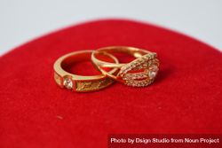 Two diamond gold wedding rings on red material with copy space bGRxaB