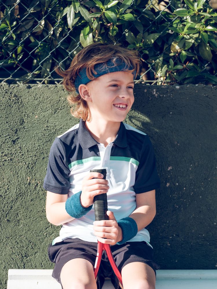 Cute preteen boy in sportswear with tennis racket