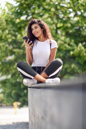 Arab woman talking on phone sitting outdoors, vertical