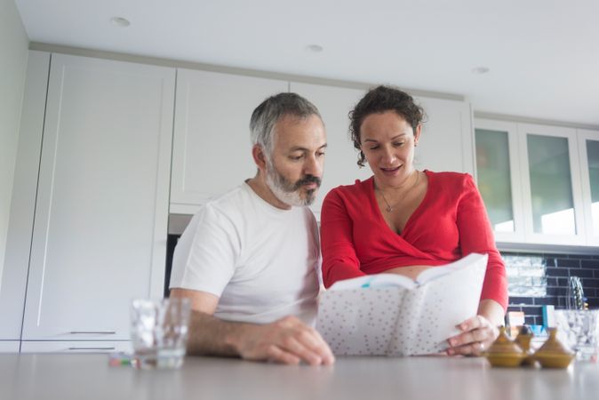 Couple going through recipes in bright kitchen