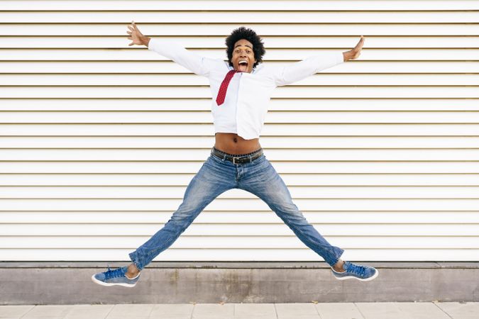 Man in jeans and dress shirt jumping for joy