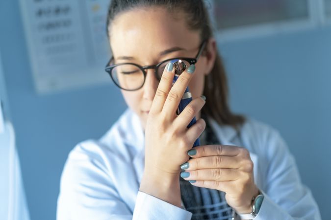 Medical woman looking through otoscope