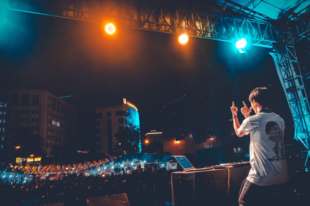 Back view of an excited standing on stage at a concert during daytime