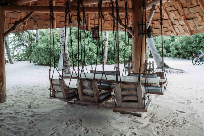 Brown wooden swing dining table on beach in Maldives