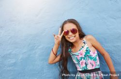 Portrait of cute little girl with sunglasses gesturing peace 0WXpr5
