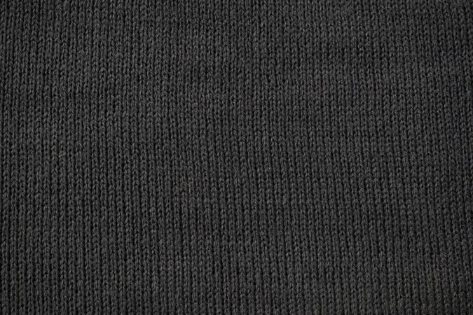 Detailed dark grey knitted fabric background texture.