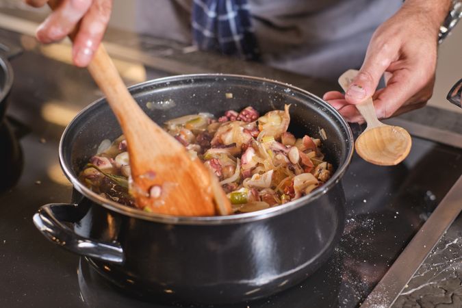 Crop man cooking food in saucepan in kitchen