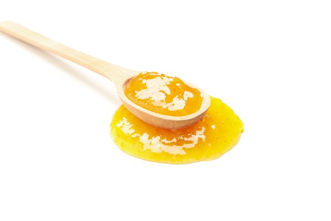 Wooden spoon with apricot jam isolated on plain background