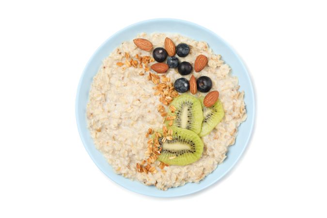 Bowl with oatmeal porridge and ingredients isolated on plain background