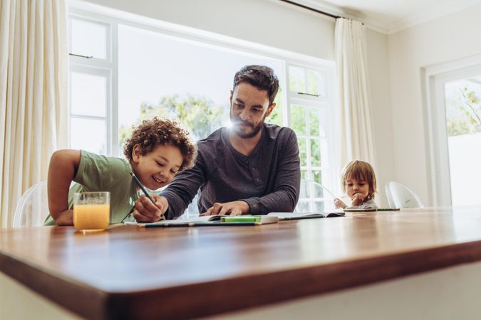 Man sitting at the table at home with his kids taking care of them
