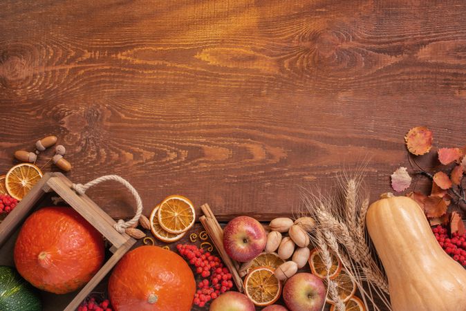 Wooden table with squash, dried orange, apples and cinnamon sticks