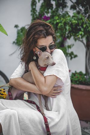 Woman kissing greyhound while relaxing on street