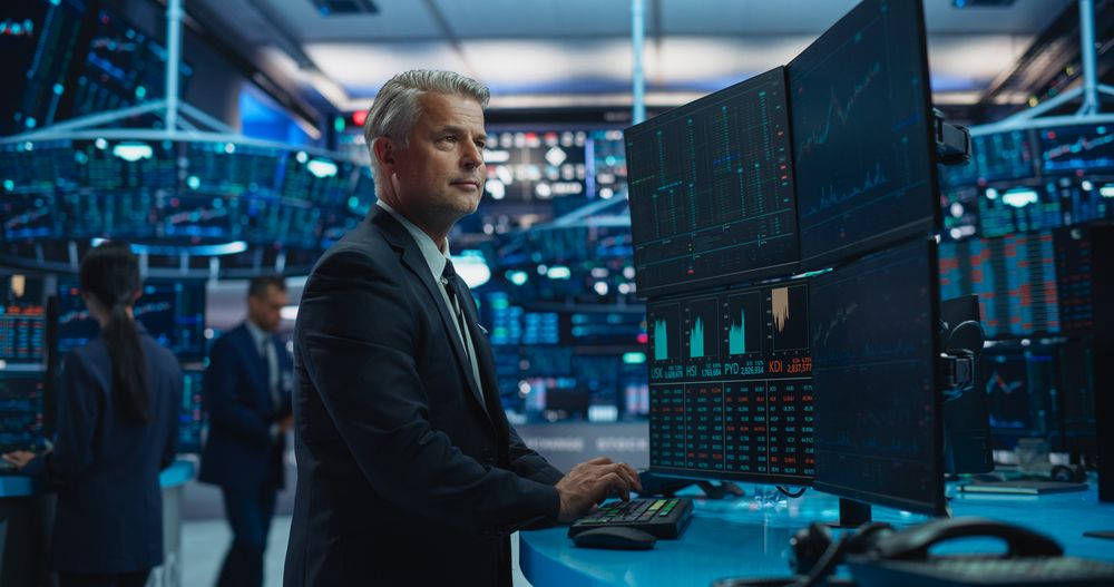 Financial Analyst Using a Desktop Computer with Multi-Monitor Workstation with Real-Time Graphs, Financial Reports and Market Charts.