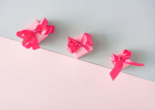 Gift boxes with pink ribbon on baby blue and baby pink background