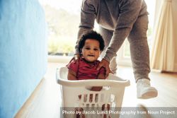 Young baby with afro smiling as his mother takes her for a ride in a basket at home 4M9gz4