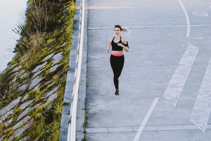 Woman running on embankment near water