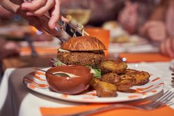 Faceless person cutting delicious burger