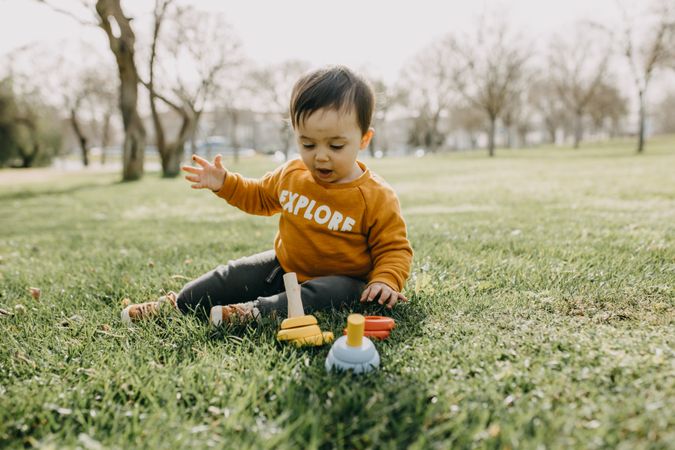 Adorable toddler with plastic toys outside