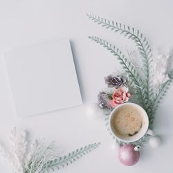 Coffee and paper card with flowers, leaves and pink Christmas decoration