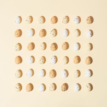 Speckled eggs  in rows on pastel yellow background