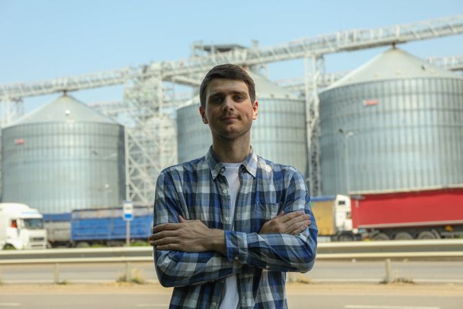 Young man against grain silos. Agriculture business