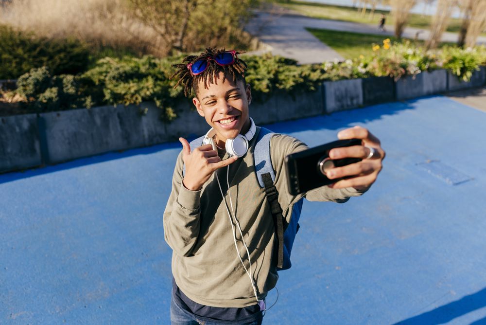 Young Black man taking selfie with smartphone