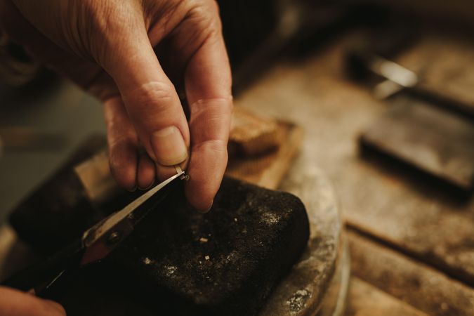 Hands of female jeweler cutting small pieces of metal for making jewelry
