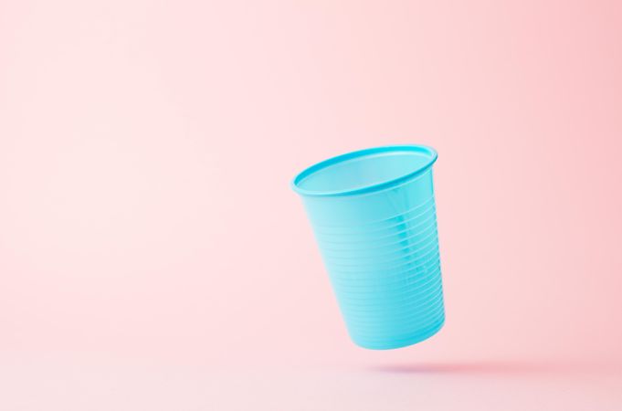 Falling blue disposable cup on pink background