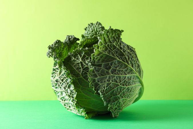 Ripe cabbage on green background, space for text