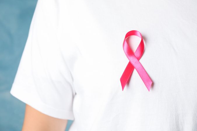 Person in t-shirt with awareness ribbon against blue background