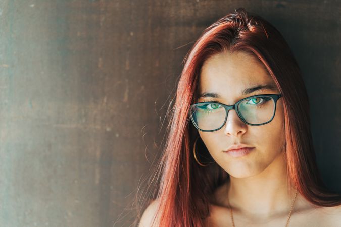 Woman in glasses leaning on wall