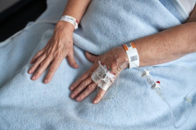 Crop unrecognizable mature woman with connected venous catheter