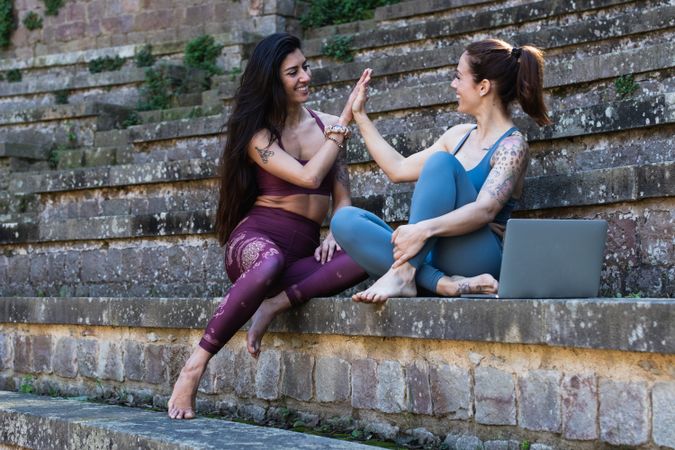 Content multiethnic women giving high five to each other before yoga lesson