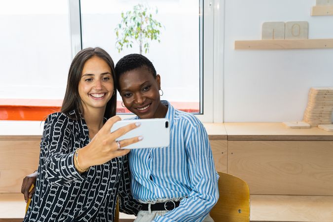 Smiling multiethnic coworkers taking selfie during break in office