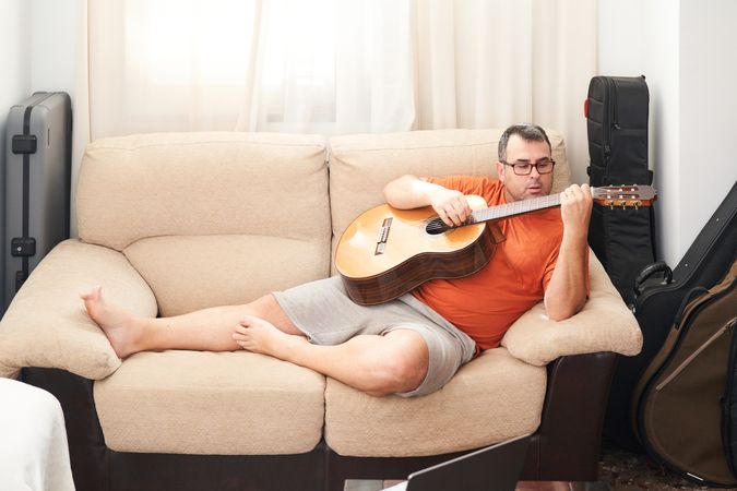 a man relaxing on the couch playing guitar