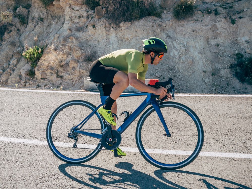 healthy man riding a bicycle on a mountain road in a sunny day