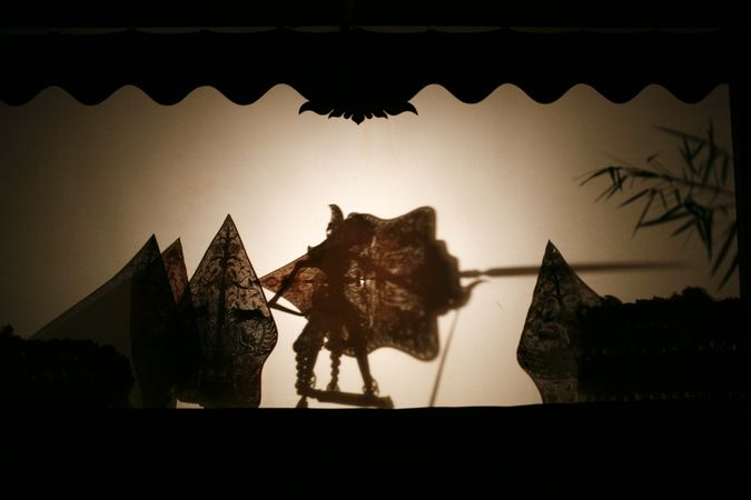 Layered shadow puppet figure holding a shield and spear