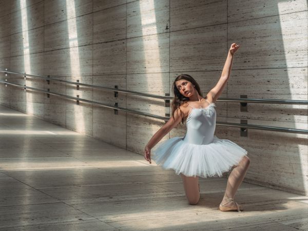 Ballerina doing ballet posing at rail in classroom