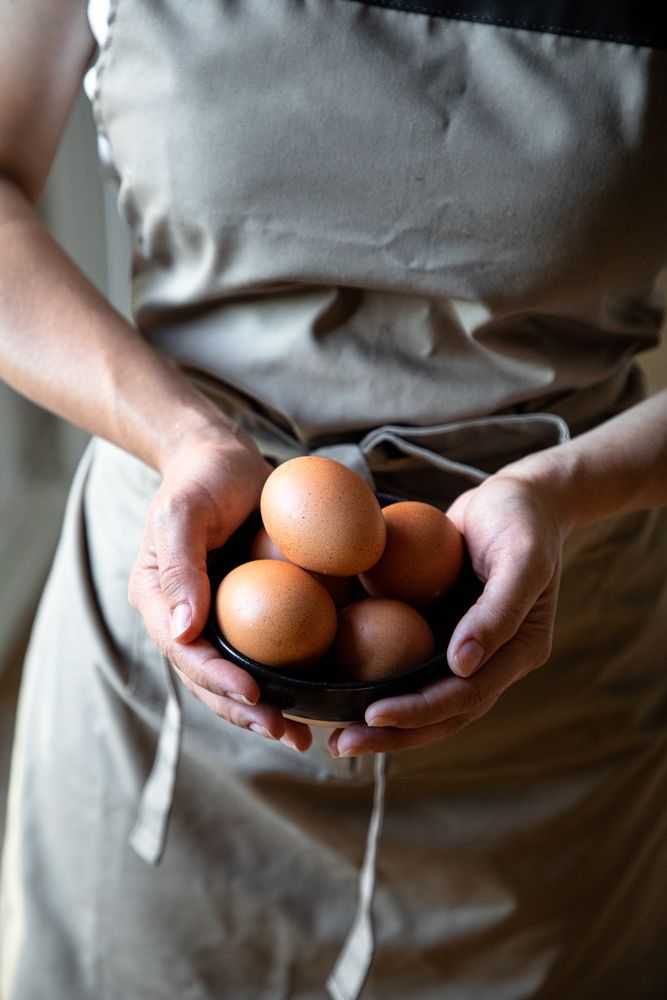 Faceless person holding bowl with eggs