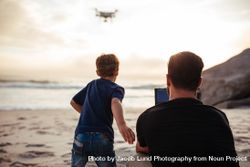 Young man with little boy enjoying flying a drone 4NqZl5
