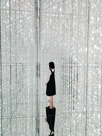 Tokyo, Japan - November 19th, 2019: Young woman standing in reflective crystalline installation