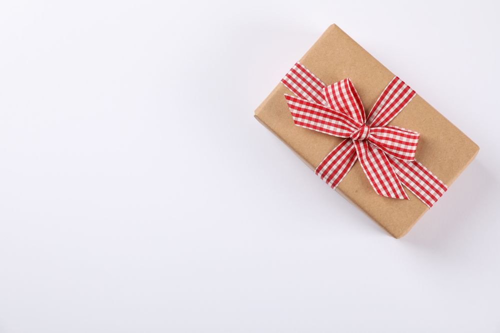 Beautiful gift box with checkered bow on blank background, space for text