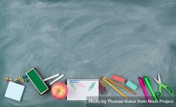 Back to school theme with erased green chalkboard and student supplies 0PRgN4