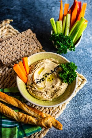 Creamy hummus and vegetables on grey kitchen counter with copy space