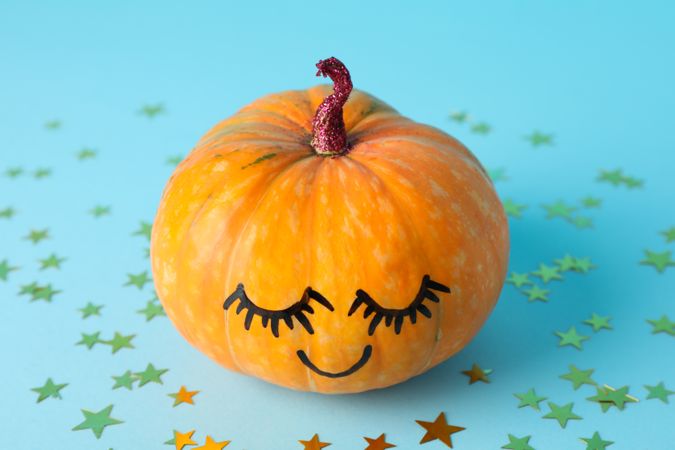Pumpkin with smile on blue decorative background, space for text
