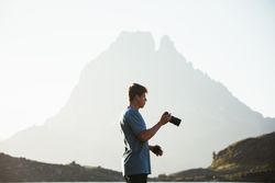 Unrecognizable man taking photo of mountain landscape
