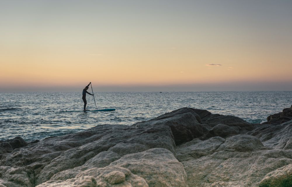 Man practicing paddle surfing with neoprene in a sunrise