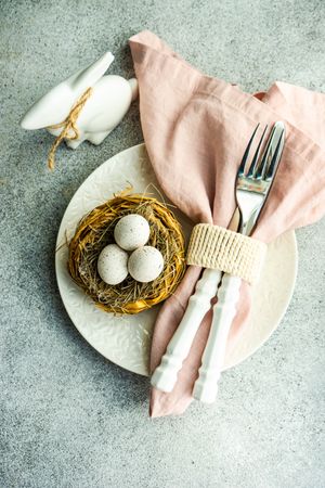 Top view of Easter table setting with bird figurine and pink napkin