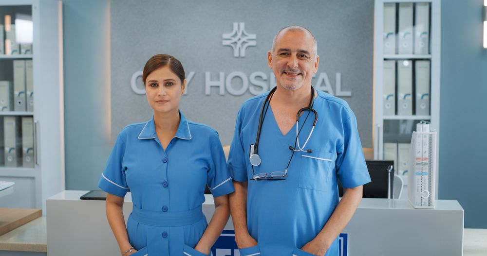 Team Portrait of a Female and Male Successful Medical Healthcare Professionals Standing in a Modern Hospital Office, Posing, Looking at Camera and Smiling