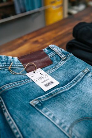 Close up of label with price and size over a blue jeans pants on industrial style store.